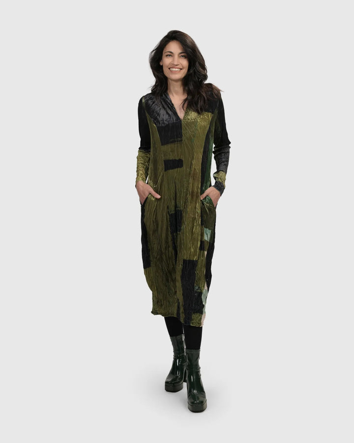 A woman wearing an Al Fresco Cocoon Dress in green and black, with a below-the-knee hem.