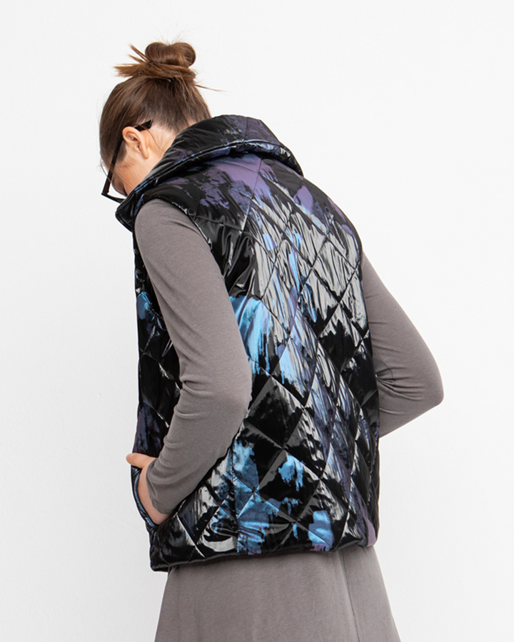 A woman wearing an Ozai N Ku faux puffer vest, black, with diamond-quilting texture.