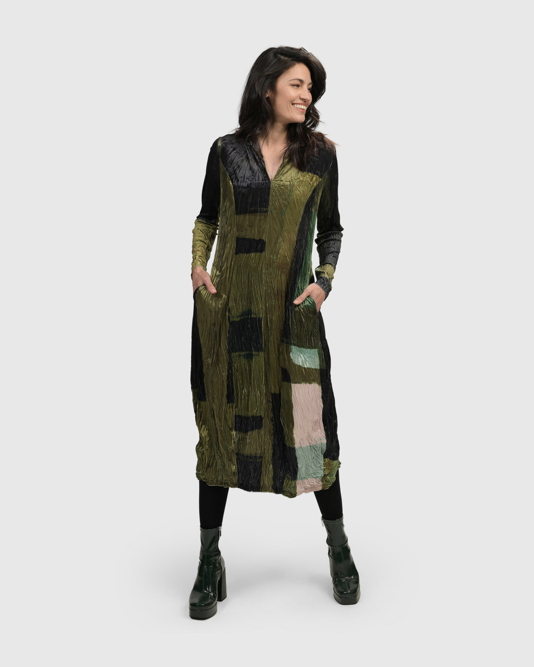 A woman wearing an Al Fresco Cocoon Dress, Olive by ALEMBIKA and black boots.