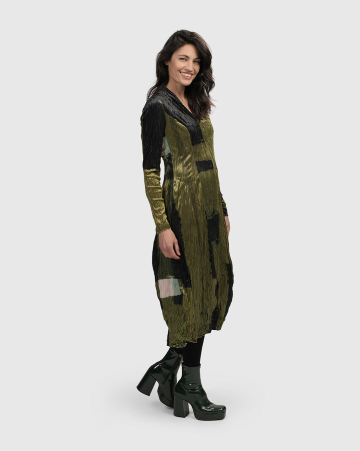 A woman wearing an Al Fresco Cocoon Dress, Olive by ALEMBIKA and black boots.