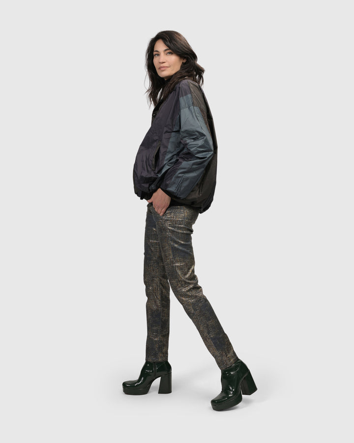 A women over 50 wearing Iconic Jeans Desires by Petrol and a camouflage jacket. Brand Name: ALEMBIKA