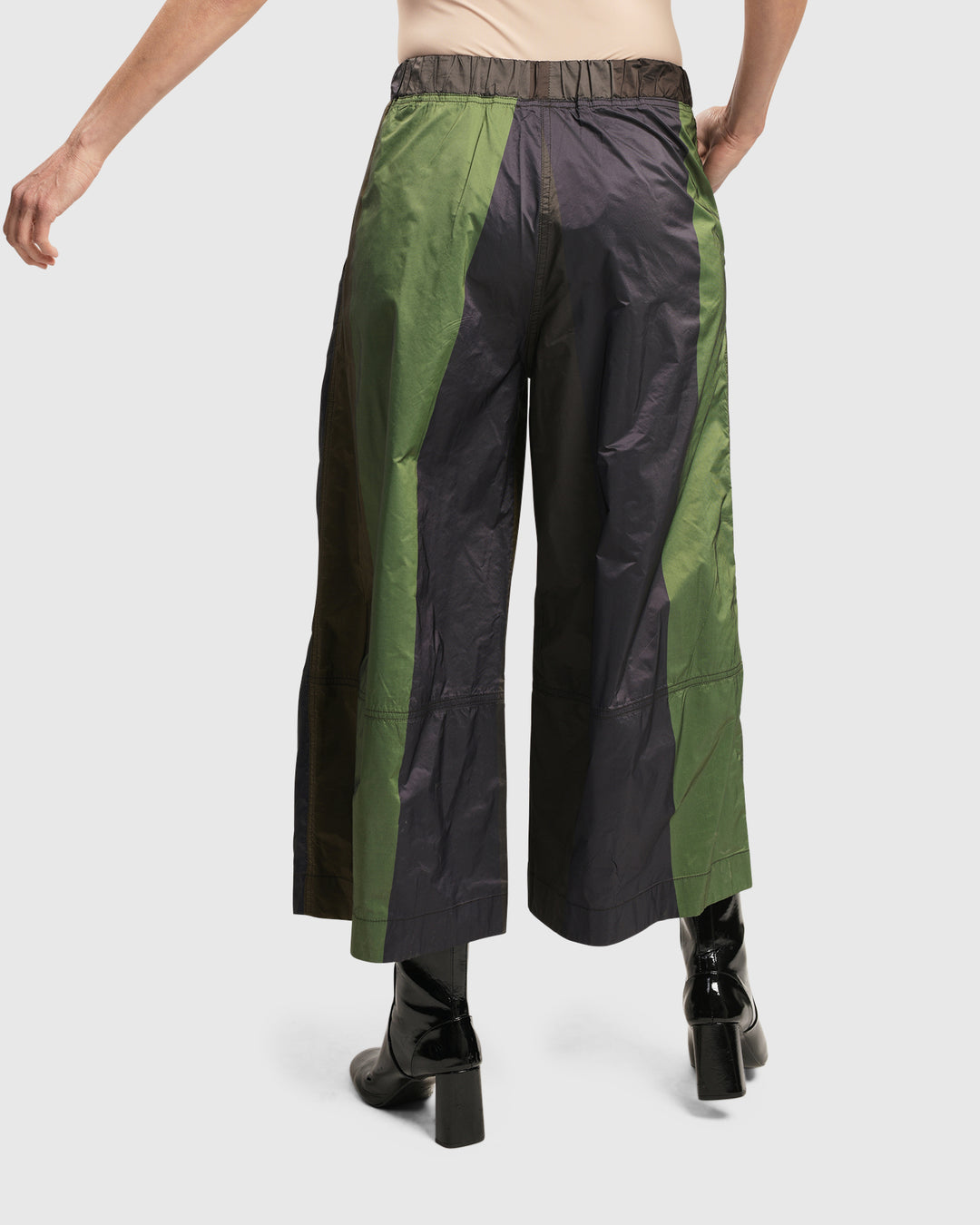The back view of a woman wearing ALEMBIKA's forest-colored woven Alfresco Market Pants with an elastic waistband.