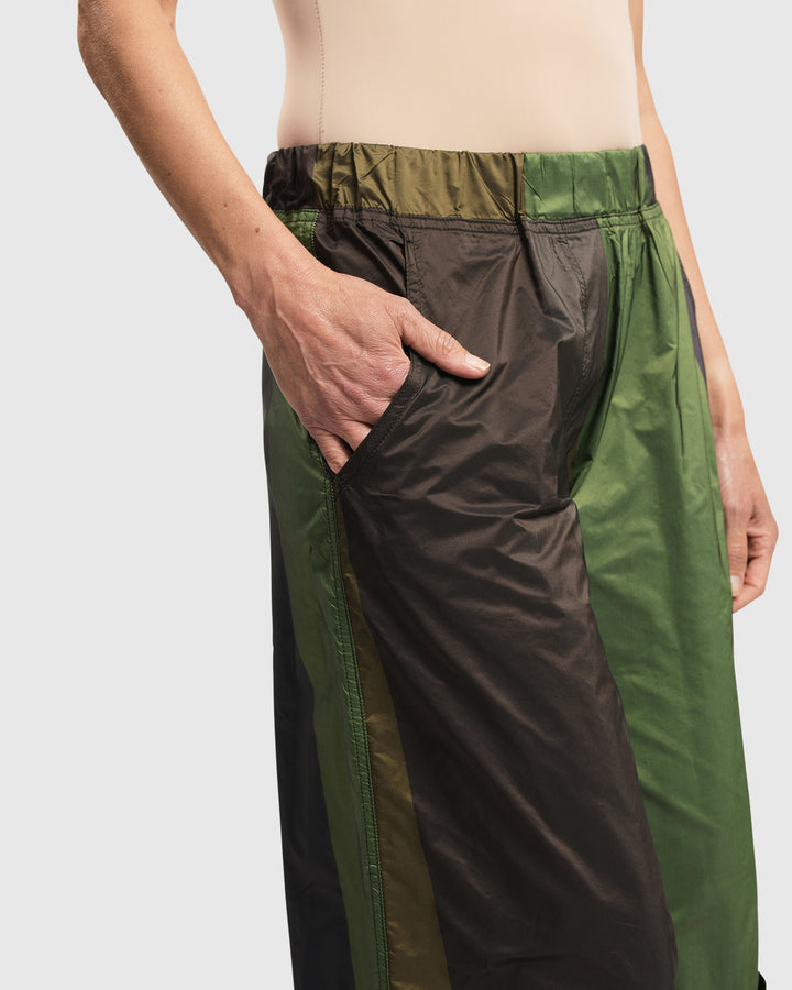A woman wearing the woven ALEMBIKA Alfresco Market Pants in Forest color with an elastic waistband.