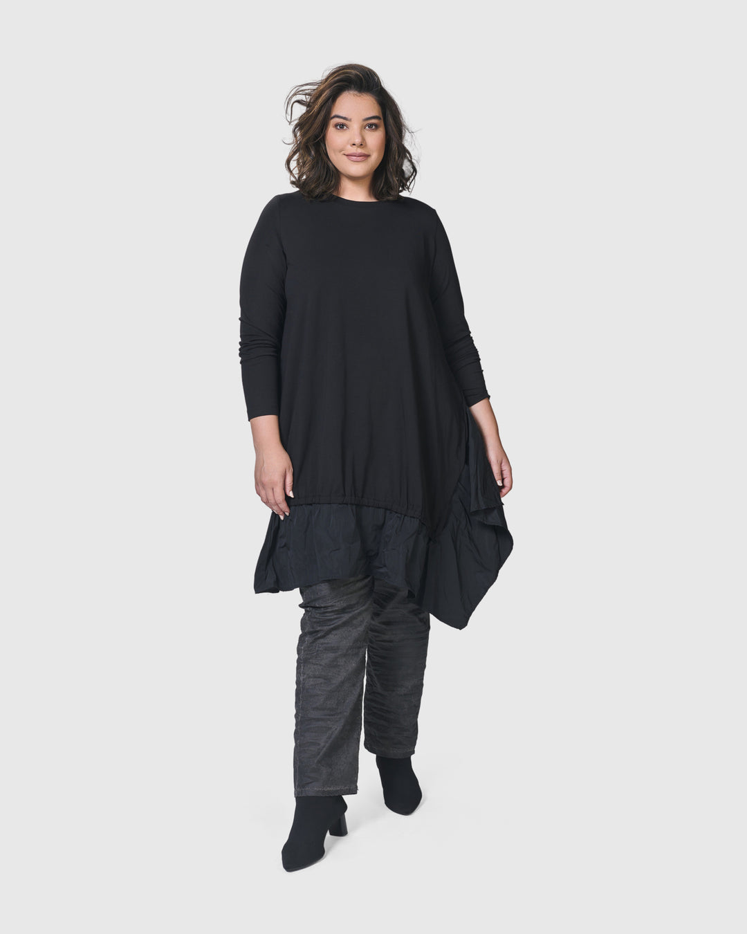 A woman wearing an ALEMBIKA Urban New Wave Tunic Top in Black with long sleeves and black pants.