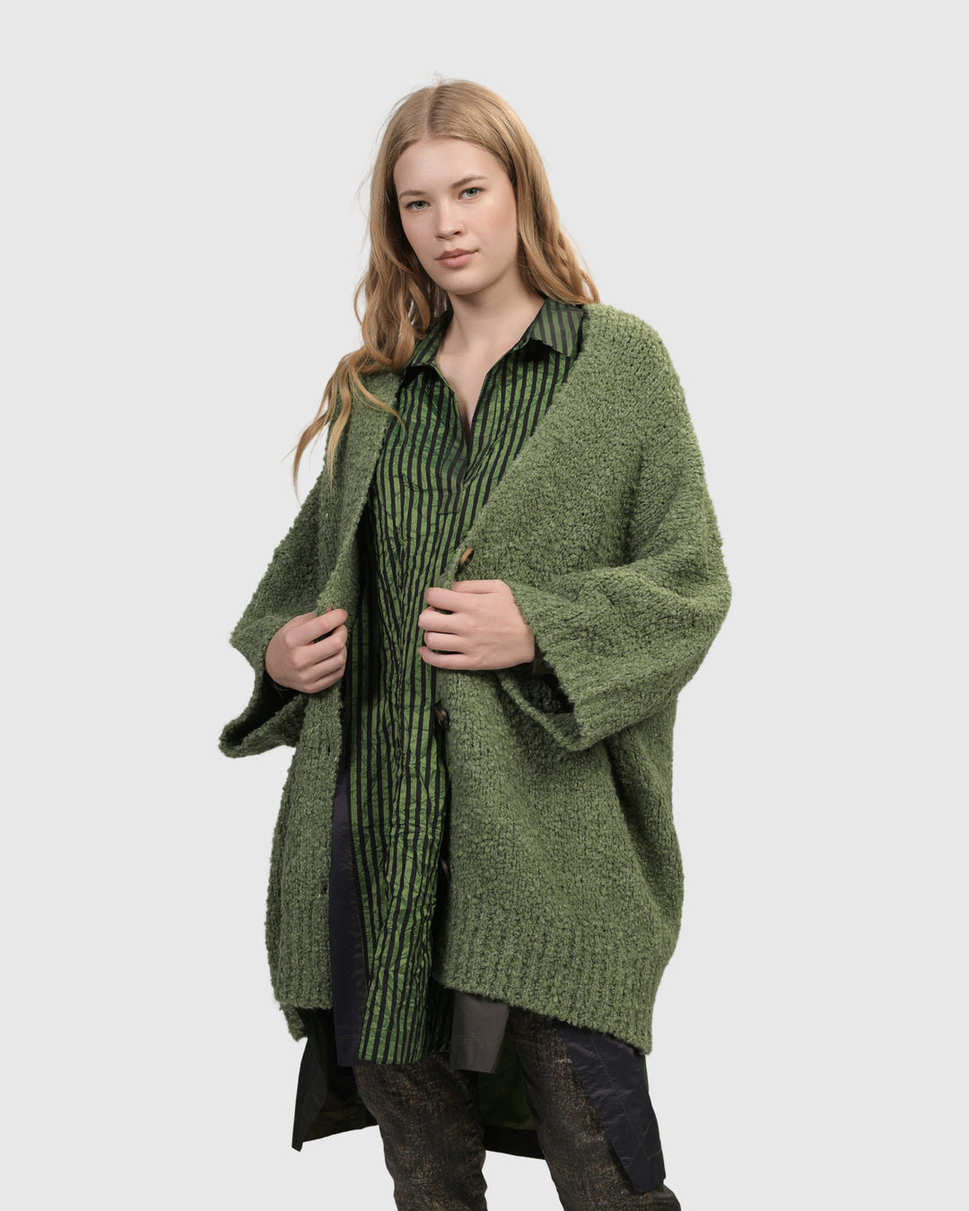 A cozy woman layering the Sunday Cardigan, Green by ALEMBIKA over black leggings.
