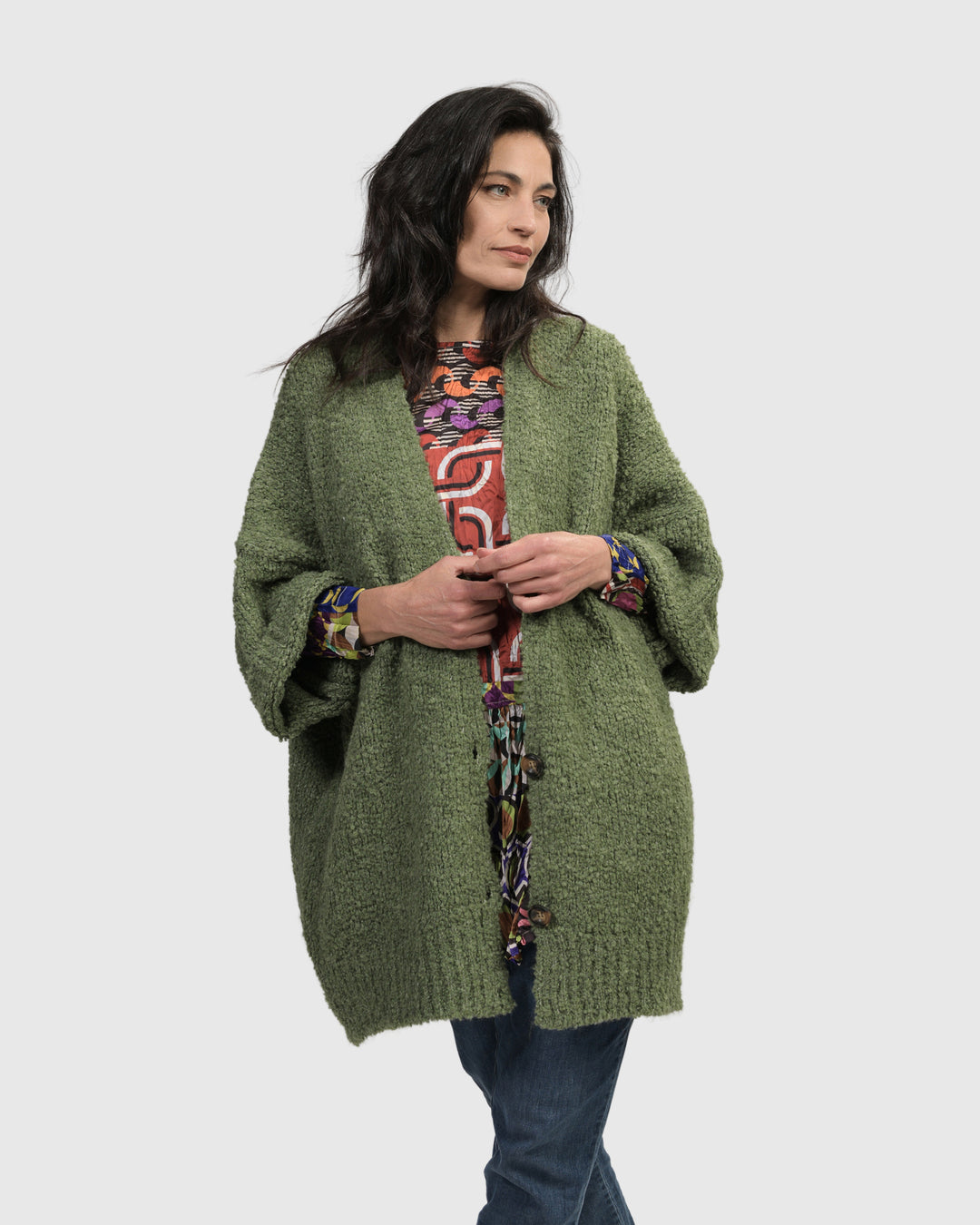 A woman wearing a cozy Sunday Cardigan in Green manufactured by ALEMBIKA.