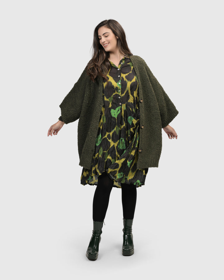 A woman in a cozy ALEMBIKA Sunday Cardigan, Hunter dress and black boots.