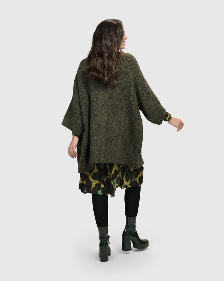 The back view of a woman wearing a cozy, ALEMBIKA Sunday Cardigan, Hunter.
