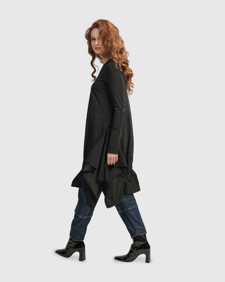 A woman wearing an ALEMBIKA Urban New Wave Tunic Top in Black with scoop neck and jeans.