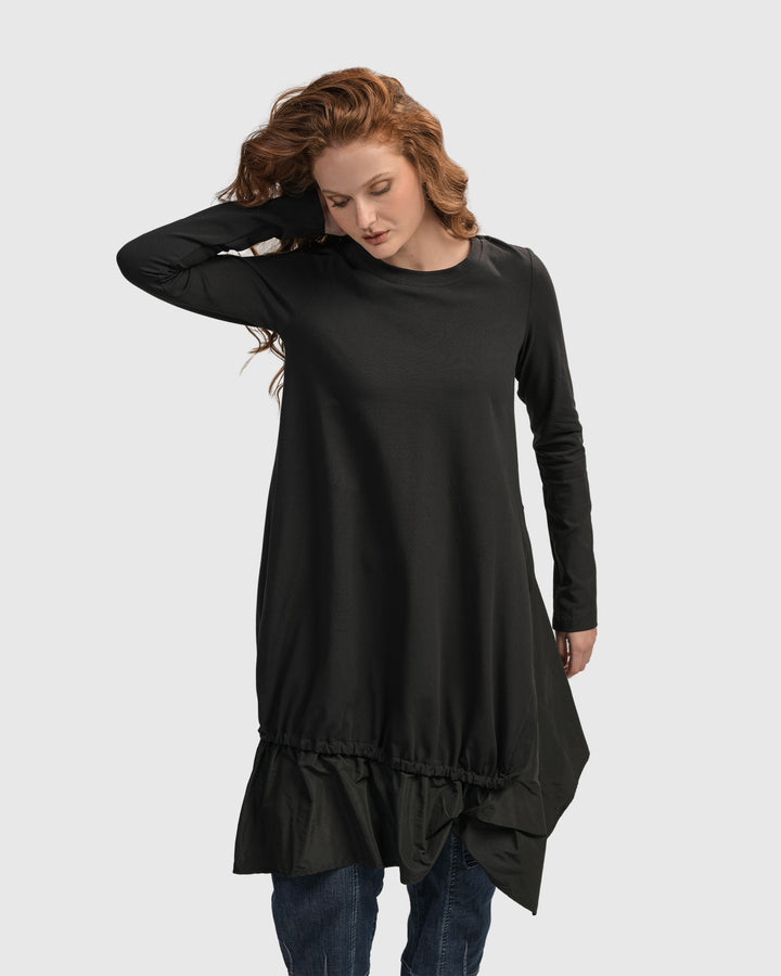 A woman wearing an ALEMBIKA Urban New Wave Tunic Top in Black with long sleeves.
